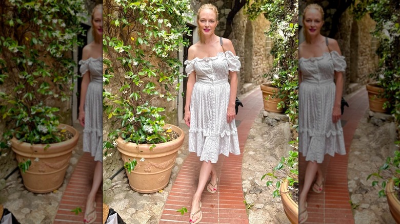 Heather Graham wearing a ponytail, breezy white dress, and sandals in a European vacation snapshot