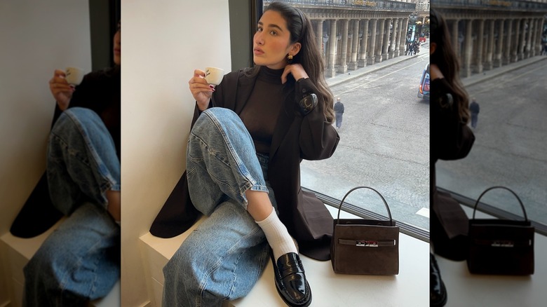 A woman at a window wearing loafers with jeans