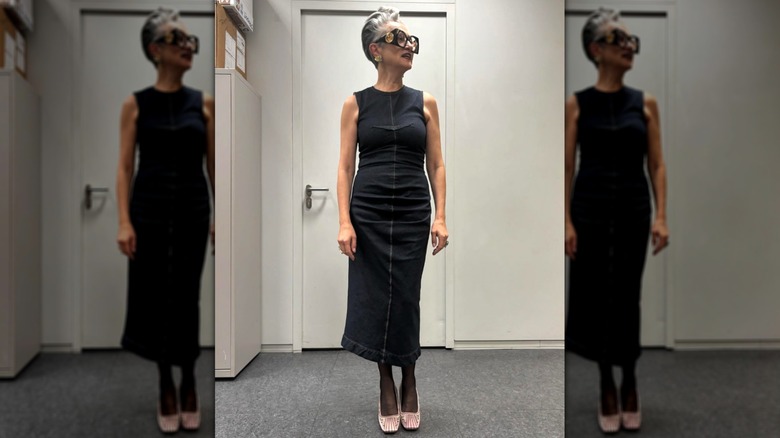 A woman in a black dress with pink satin shoes and statement glasses