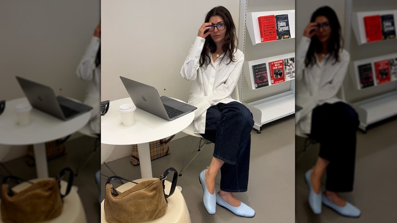 A woman wearing baby blue ballet flats at a desk