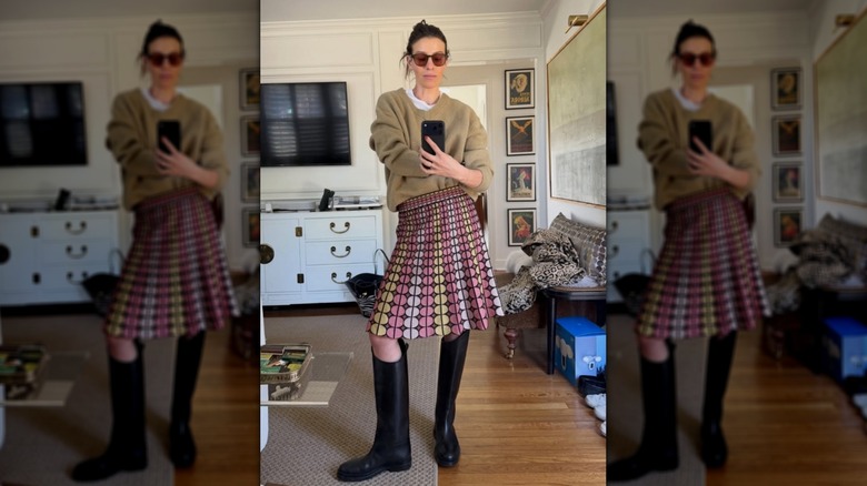 A woman in tall boots and a skirt and sweater