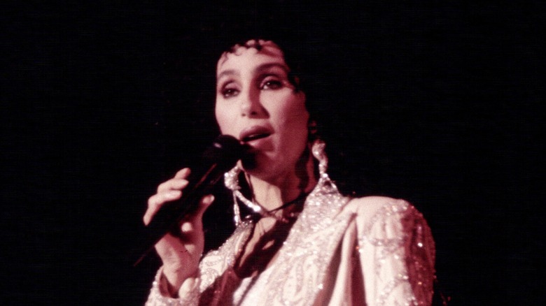 Cher performing on stage in a bedazzled outfit in 1990