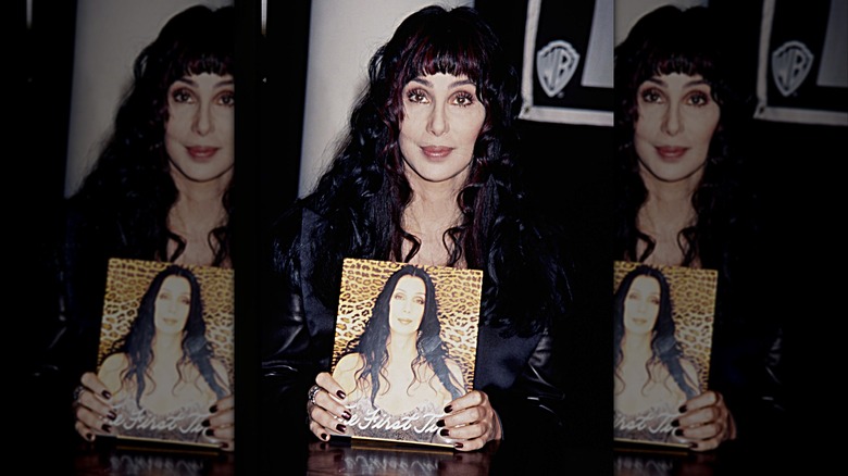 Cher holding a copy of her book "The First Time" in 1998