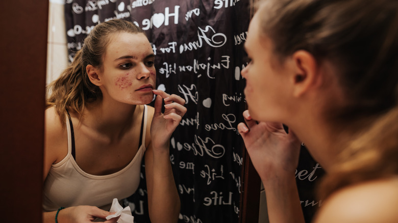 Woman examining skin in mirror