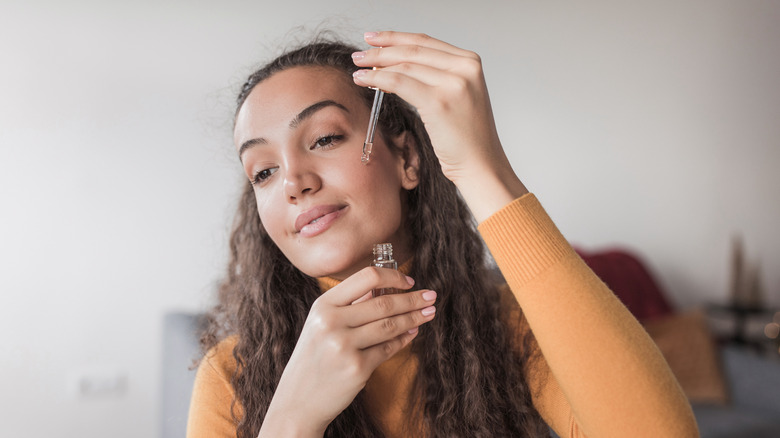 Woman applying serum to her face