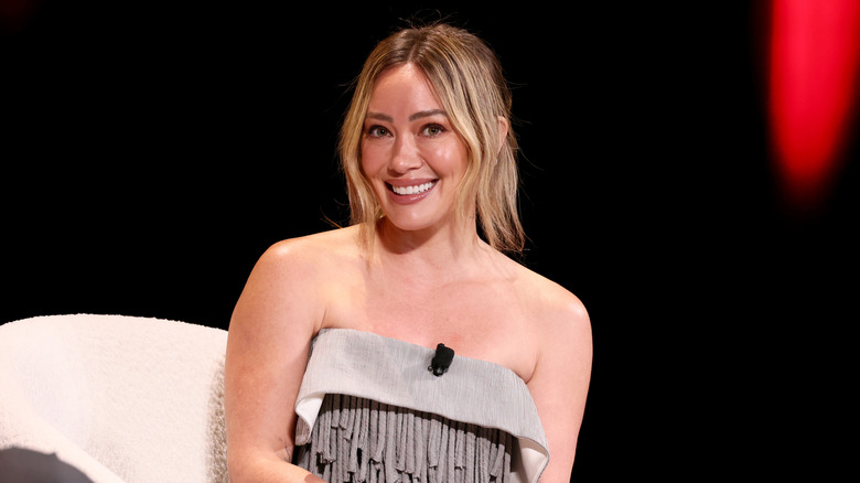 Hilary Duff sitting on a stage