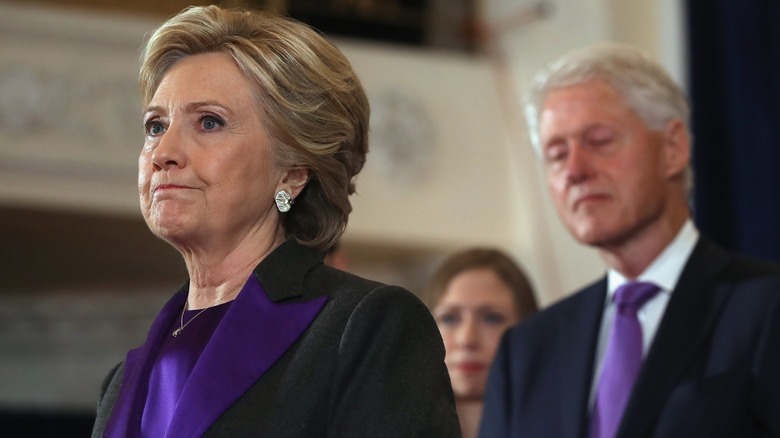 Hillary Clinton standing in front of Bill Clinton
