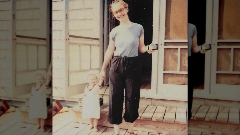 Hillary Clinton holding hands with a young Chelsea Clinton in 1981 while wearing a blue t-shirt and black pants