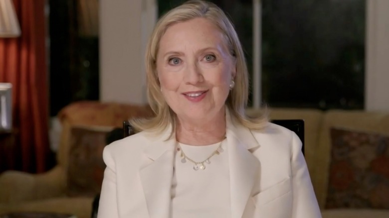 Hillary Clinton sitting in her home wearing a white jacket and matching shirt in 2020