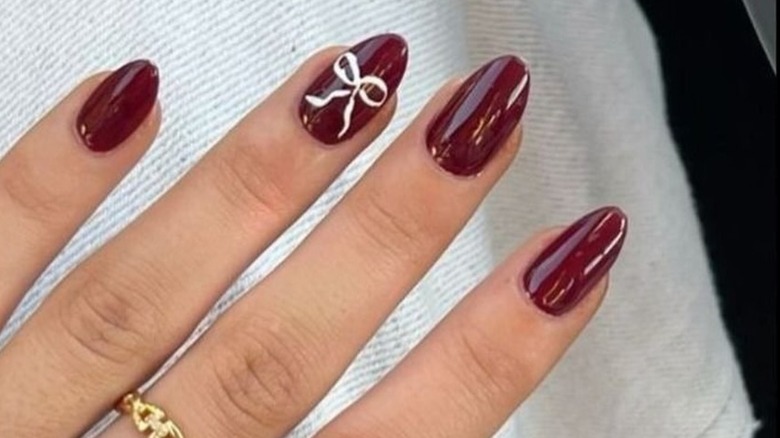 Maroon nails with a white bow accent nail