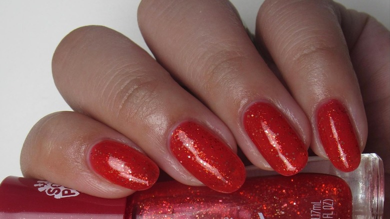 A person with sparkly red nails