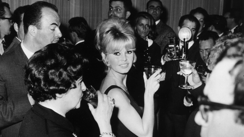 Brigitte Bardot smiles with a blond beehive hairstyle.