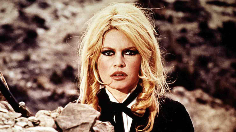 Brigitte Bardot frowns wearing dark eye makeup and a black-and-white suit