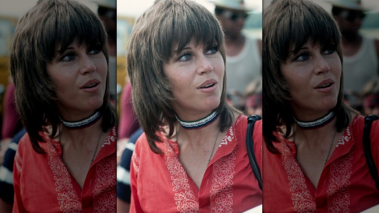 Jane Fonda poses with a brunette wolf cut with a heavy fringe and thick side burns.