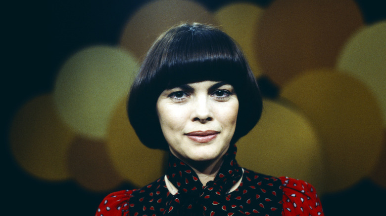 Mireille Mathieu poses with a short brunette bowl cut hairstyle.