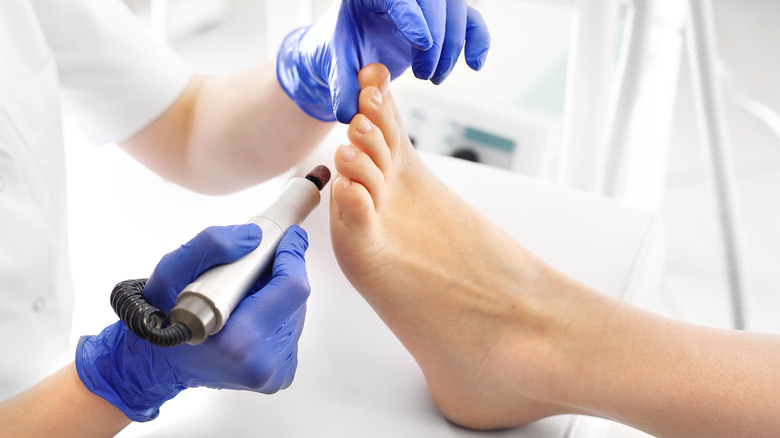 A nail tech removing calluses