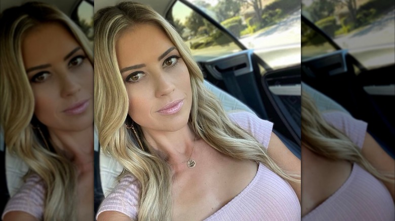 Christina Haack in the car in a pink shirt taking a selfie
