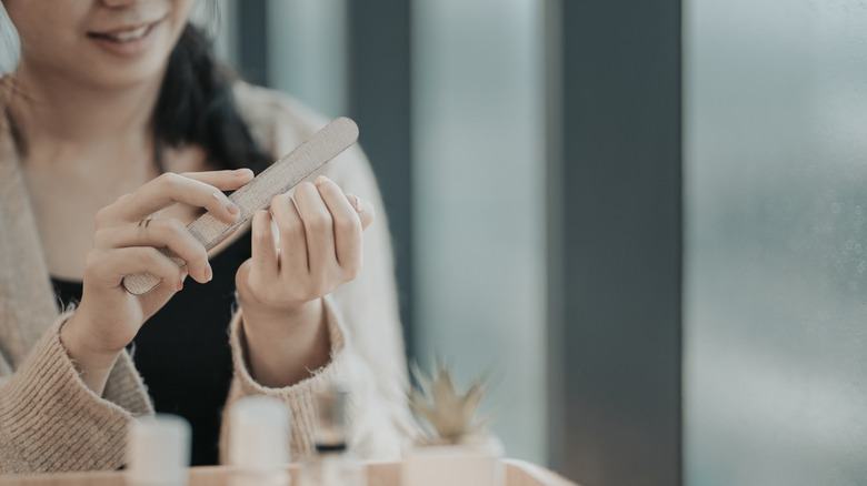 Woman filing nails at home