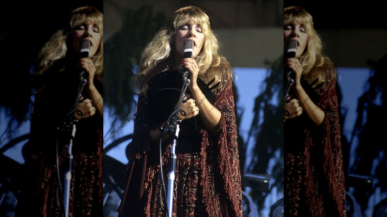 Stevie Nicks onstage singing in an embroidered, burgundy shawl