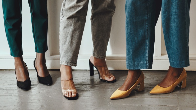 Three women standing in a line wearing differently heeled shoes