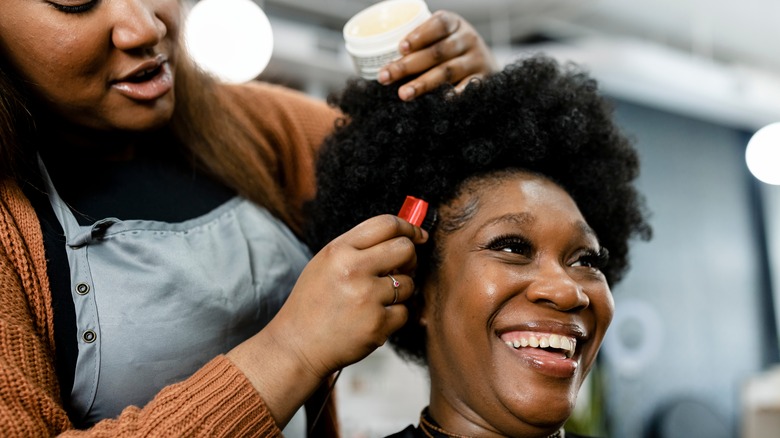 A hair stylist works on a client's edges at a hair salon