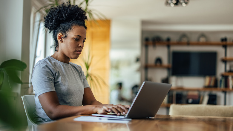 A woman types on her laptop