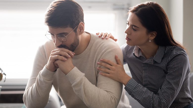 Woman touching withdrawn man