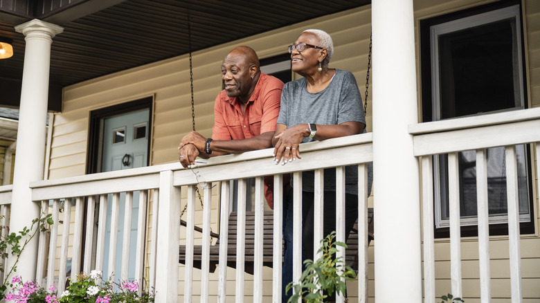 A mature couple leaning over a porch railing