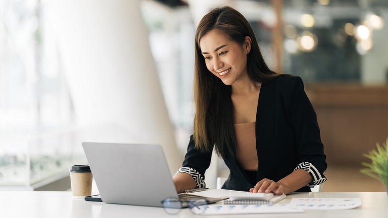 Cheerful woman smiling at laptop