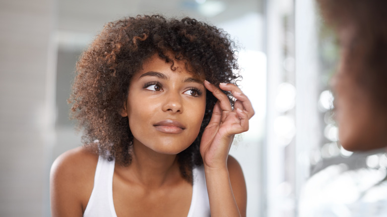 Woman examining brows in mirror