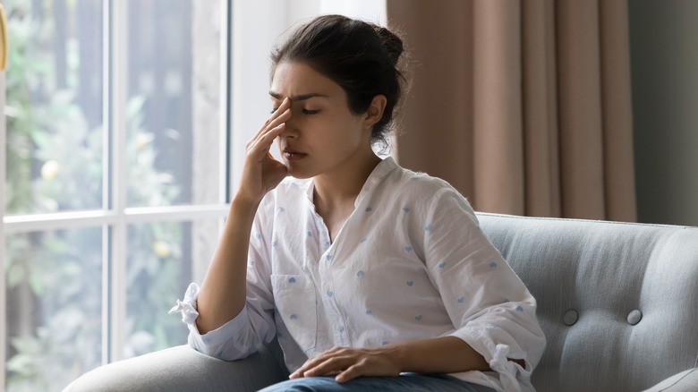 woman on couch holding face