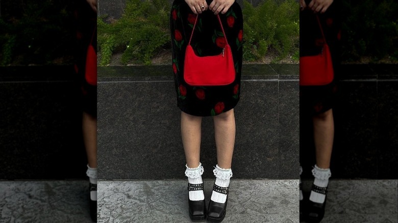 Closeup of person holding red purse wearing floral dress