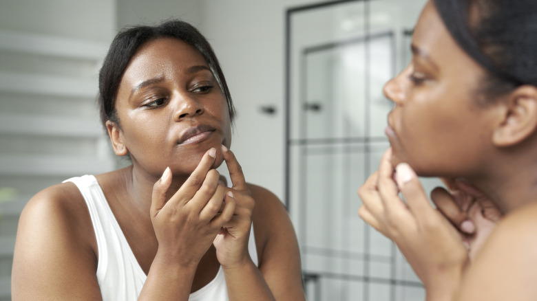 Woman checking skin for blemishes