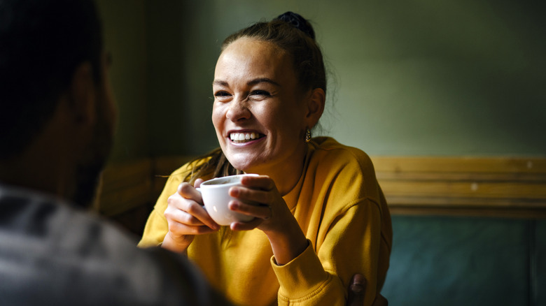 A woman holding a teacup and laughing