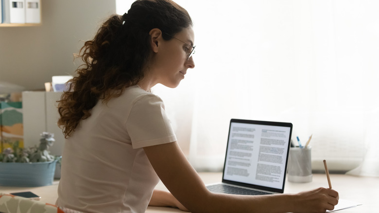 Woman sitting at her laptop and taking notes