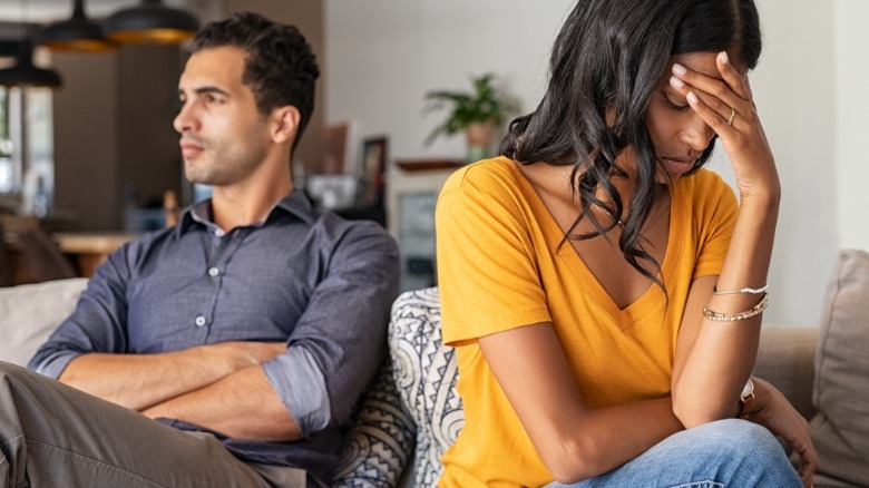 Couple sitting on couch, looking away after arguing