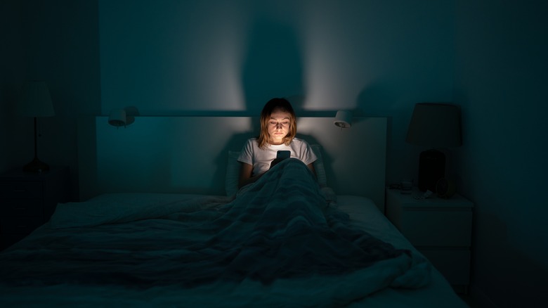 Exhausted woman on phone in bed