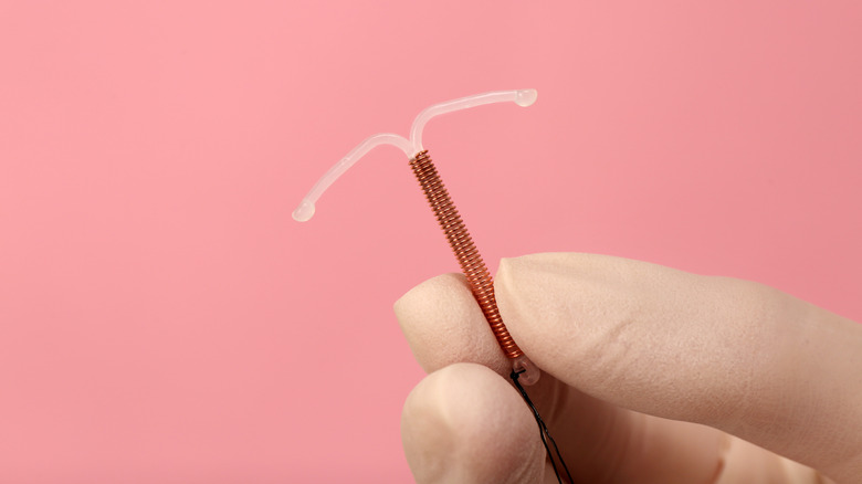 Woman holds IUD and smiles