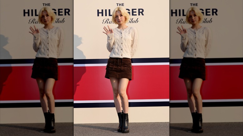 Kpop idol Yeji attending a Tommy Hilfiger event in a knitted cardigan, mini-skirt, and chelsea boots