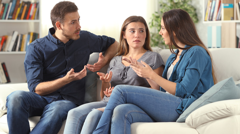 A multigenerational family sitting around a table and toasting with glasses of red wine