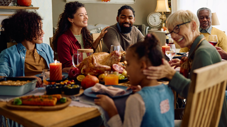 A multi-generational family sitting around a table with a roast turkey
