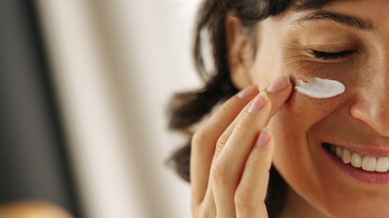 A woman applying moisturizer to her skin