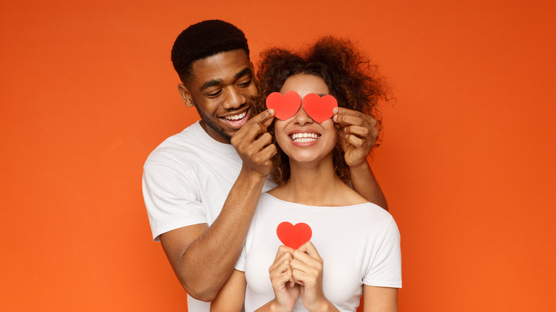 Man covering woman's eyes with hearts