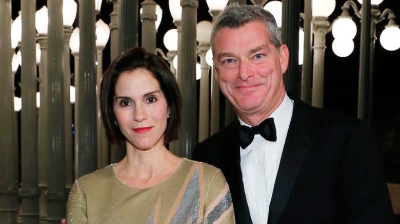 Jami Gertz and Tony Ressler posing together in front of a series of lights at a 2015 event