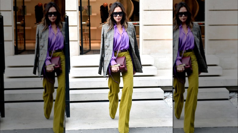 Victoria Beckham wearing purple shirt and green pants