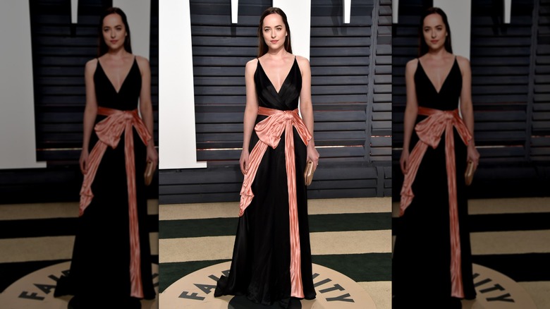 Dakota Johnson wearing a black gown with her hair half-pulled back at the Vanity Fair Oscar's Party