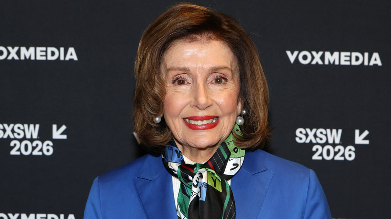 Nancy Pelosi smiling on step-and-repeat