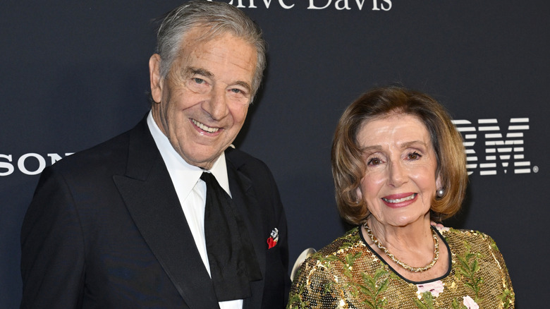 Paul and Nancy Pelosi smiling on step-and-repeat