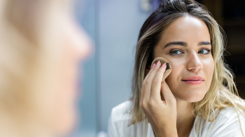 Woman applying makeup in mirror