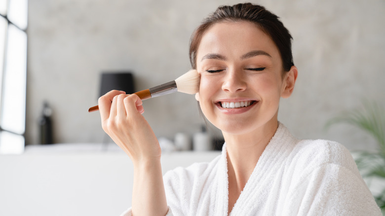 A woman applying powder on her face